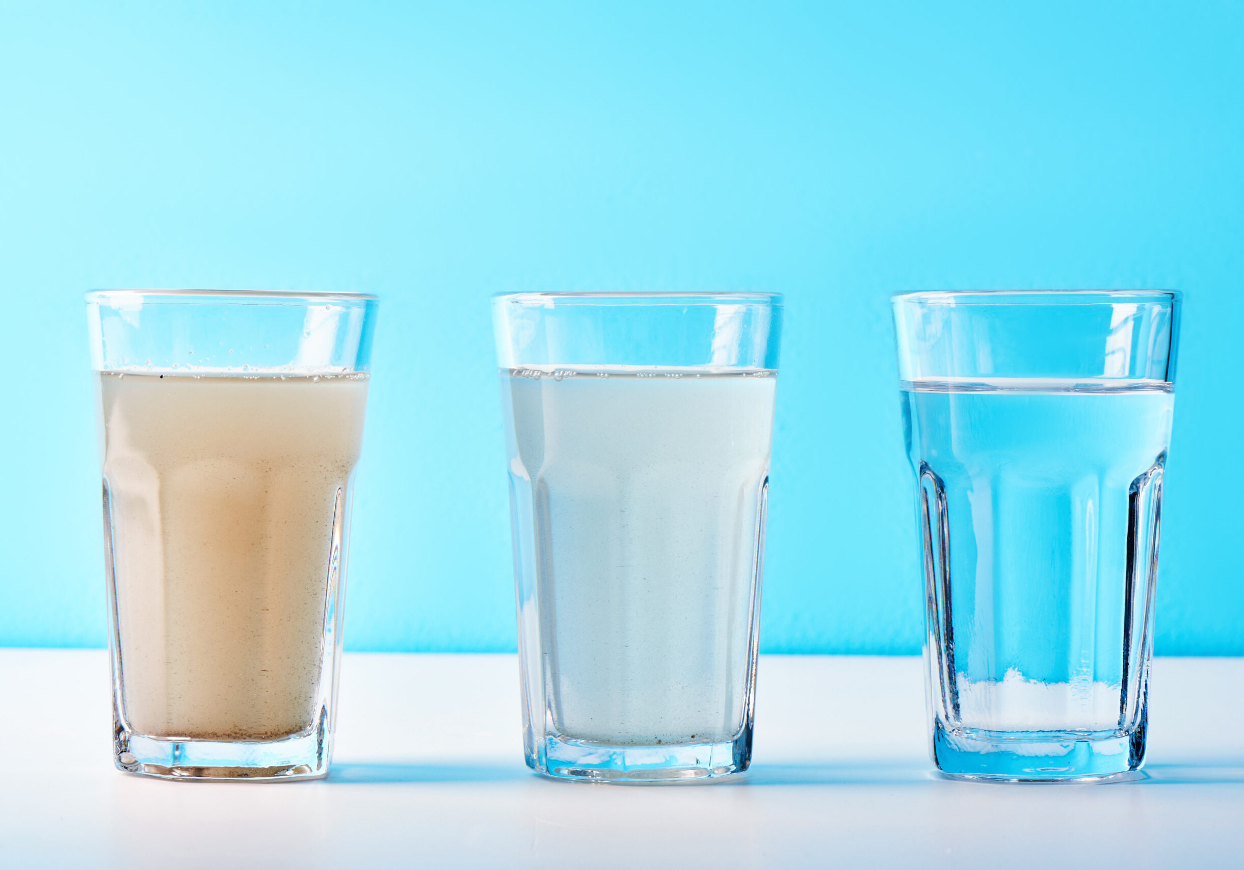 Water filters. Concept of three glasses on a white blue background. Household filtration system.