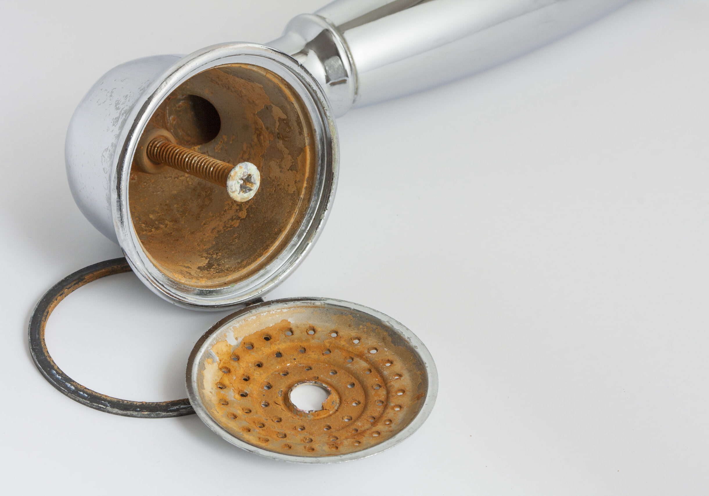 Broken rust-eaten shower head with limescale and rust stains on it Broken shower head with limescale and rust on it